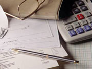 Picture of checks and paperwork by calculator on table.